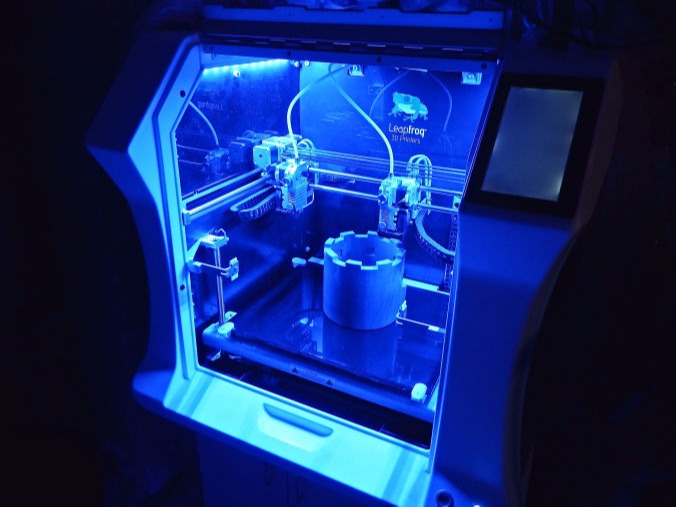 blau beleuchteter 3D-Drucker mit großem 3D-Modell im Druckraum